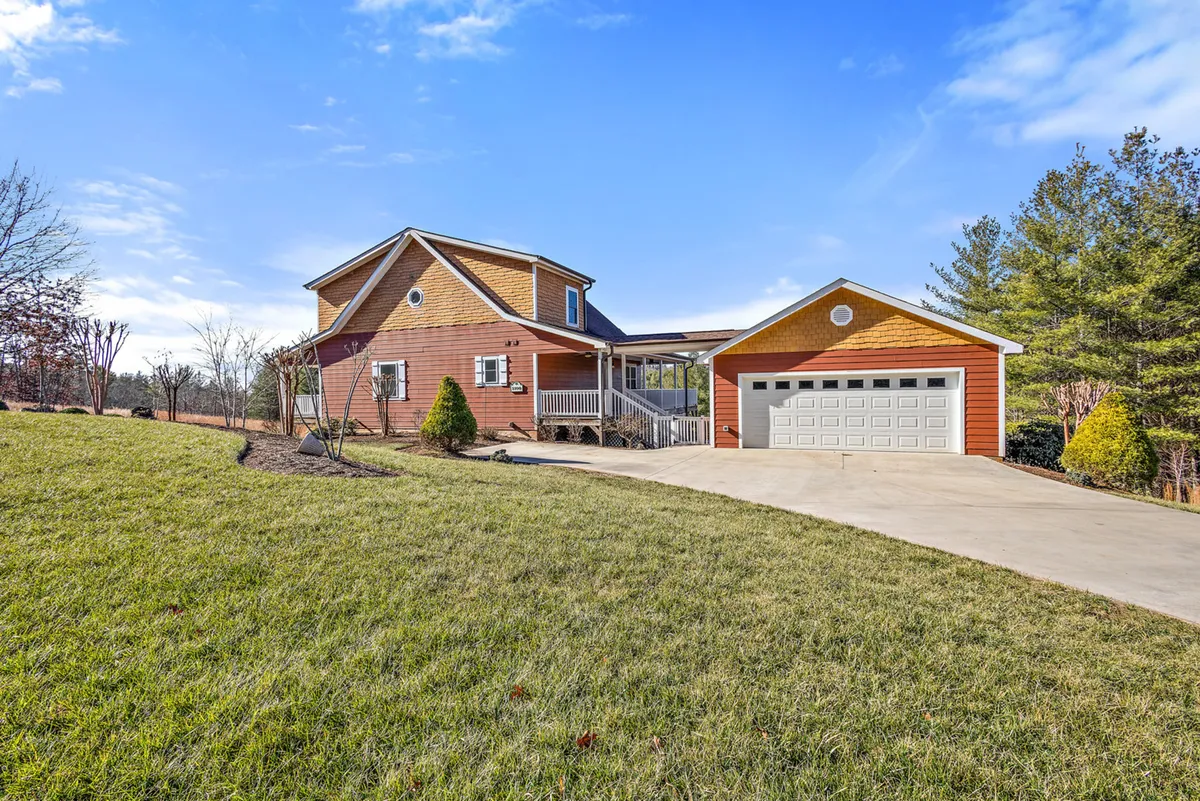 This image showcases the exterior of House Galini, featuring a welcoming facade, a spacious front porch for relaxing, a visible garage, and a beautifully landscaped yard. The green lawn and open space hint at room for family gatherings and outdoor play.