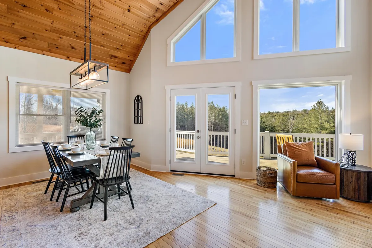 A welcoming dining area with a spacious table, large windows, and a view of the outdoor deck. The scene suggests lively family meals and easy access to the deck for cookouts or outdoor dining, merging indoor and outdoor living.