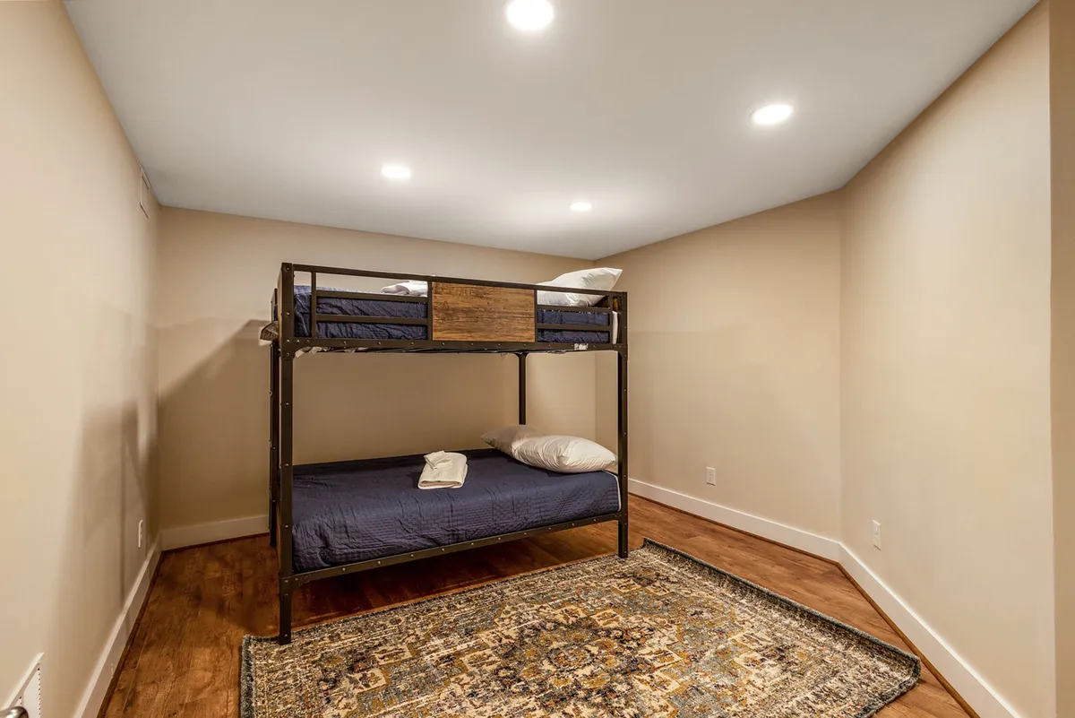 A comfortable bunk room setup with a full-over-full bunk bed, plush pillows, and an area rug. The cozy nook is inviting and perfect for children or friends sharing a space, echoing the family-friendly layout of the house.