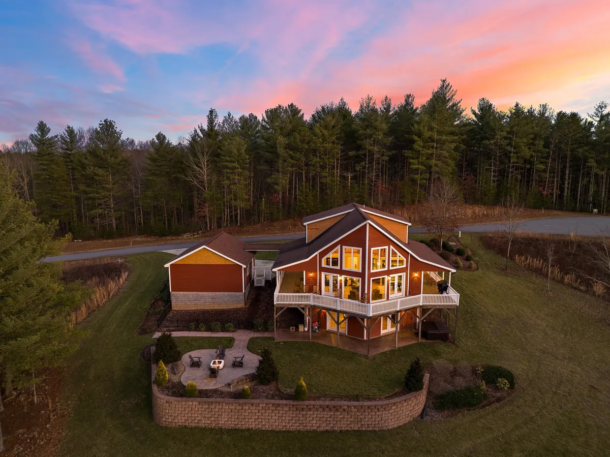 This image captures the exterior of House Galini at sunset, highlighting the patio area, surrounding trees, and a warm, welcoming sky. The scene shows how the home sits in the midst of lush nature, inviting guests to step outside and embark on outdoor adventures. Family and friends can be seen gathering around a fire pit, with the expansive forest just beyond, setting the stage for exploration.